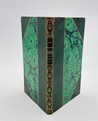 un vieux livre à la couverture verte posé sur une table blanche