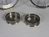 two silver dishes on a table with a clock in the background