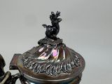 a silver tea pot with a bird on top of it