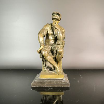 bronze statue of a man sitting on a stool with a dog