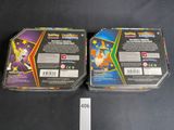 two boxes of pokemon trading cards sitting on a table