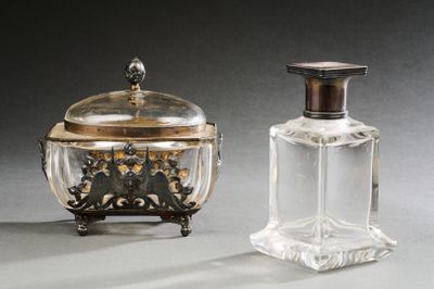 une paire de flacons de parfum en argent et en verre, munis de couvercles, posés sur un support gris