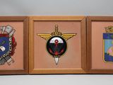 trois photos encadrées représentant différents insignes militaires, accrochées au mur