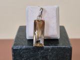 un petit pendentif en verre posé sur un bloc de marbre, sur une table