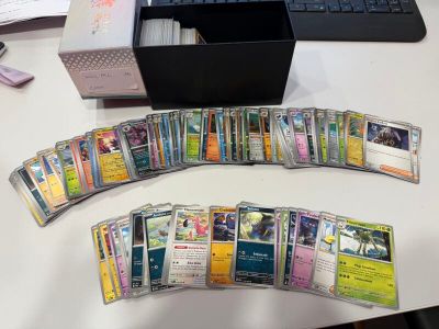 a lot of pokemon cards on the desk next to a keyboard