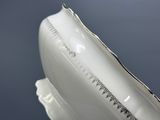 un vase blanc bordé d'argent posé sur une table