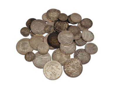 a pile of old silver coins on a white surface