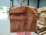 a person holding a brown piece of luggage in a warehouse