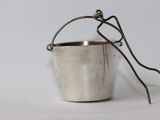 a small metal bucket with a handle on a white surface