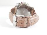 someone is holding a watch with a pink strap on a white surface