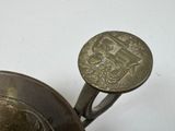 a silver vase with a coin on top of it