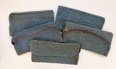 plusieurs morceaux de tissu bleu ornés de coutures rouges, posés sur une surface blanche