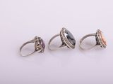 three rings with different colored stones on them on a white surface