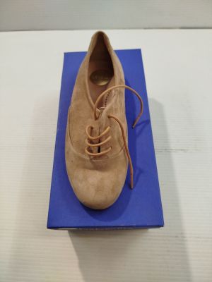 chaussures beiges en daim à lacets, posées sur une boîte bleue, sur une surface blanche