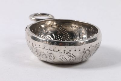 un bol en argent avec une poignée sur une surface blanche
