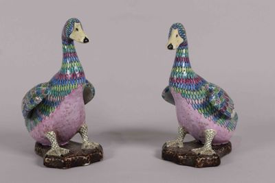 pair of colorfully painted ceramic ducks sitting on top of a wooden base