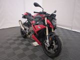 une photo d'une moto rouge et noire garée sur un sol à damier noir et blanc