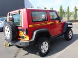 a red jeep parked in a parking lot next to a building