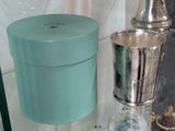 a blue box sitting on a glass shelf next to a silver cup
