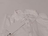 white shirt with a tag on it sitting on a white surface