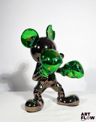 une statue de Mickey Mouse verte et noire posée sur une surface blanche