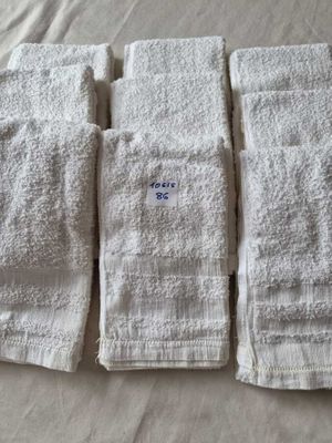 Quatre serviettes blanches sont alignées sur un lit recouvert d'un drap blanc