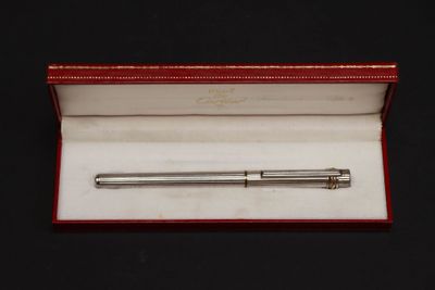 un stylo à bille argenté dans une boîte rouge posée sur une surface noire
