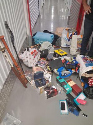 un homme debout à côté d'un tas d'objets divers posés par terre