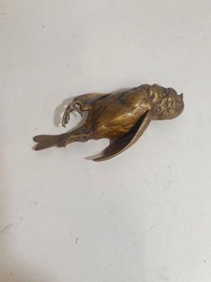 a bronze frog that is sitting on a white surface