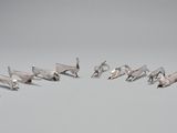 plusieurs figurines d'oiseaux en argent disposées en cercle sur une surface grise