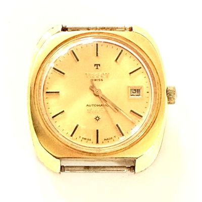 gros plan d'une montre en or sur une surface blanche