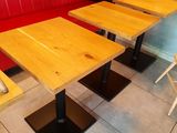 tables and benches in a restaurant with a stone wall behind them