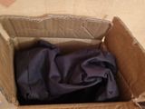 a person opening a cardboard box with a purple shirt in it