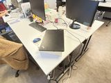 un homme assis à une table sur laquelle se trouvent deux ordinateurs portables
