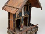 a small wooden building with a roof and a cross on top