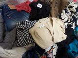 une valise pleine de vêtements et un chapeau posé sur un lit