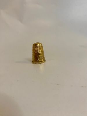 un dé à coudre doré sur un fond blanc