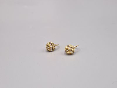 une paire de petites boucles d'oreilles en or sur une surface blanche