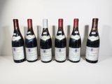 six bottles of wine are lined up in a row on a table