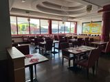 des tables et des chaises dans un restaurant doté de grandes baies vitrées et d'un tableau accroché au mur