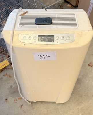 un petit climatiseur posé par terre devant une clôture