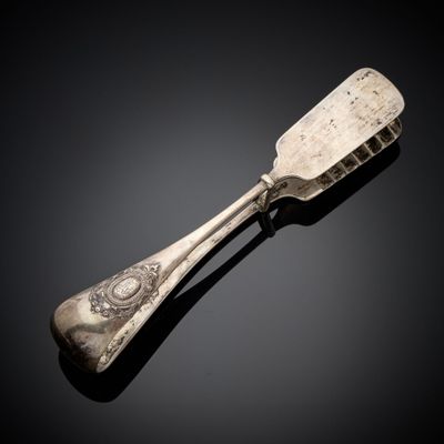 une cuillère en argent avec un manche, posée sur une surface noire