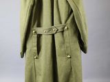a green coat hanging on a hanger on a white wall