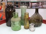 several different colored glass vases on a red tray in a glass case
