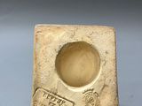 an old stone ashtray with a stamp on it on a gray surface