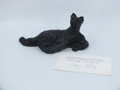 a black cat figurine sitting on a white surface next to a piece of paper