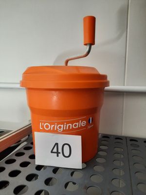 un gobelet orange muni d'un couvercle et d'une anse, posé sur une étagère
