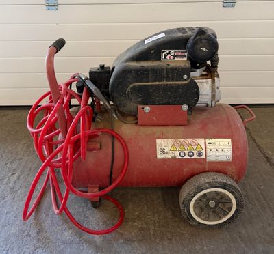 a red air compressor sitting on the floor in a garage