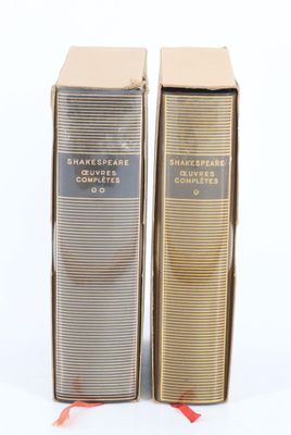 deux boîtes de parfum posées sur une surface blanche, ornées d'un ruban rouge