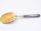 a silver spoon with a gold handle on a white surface